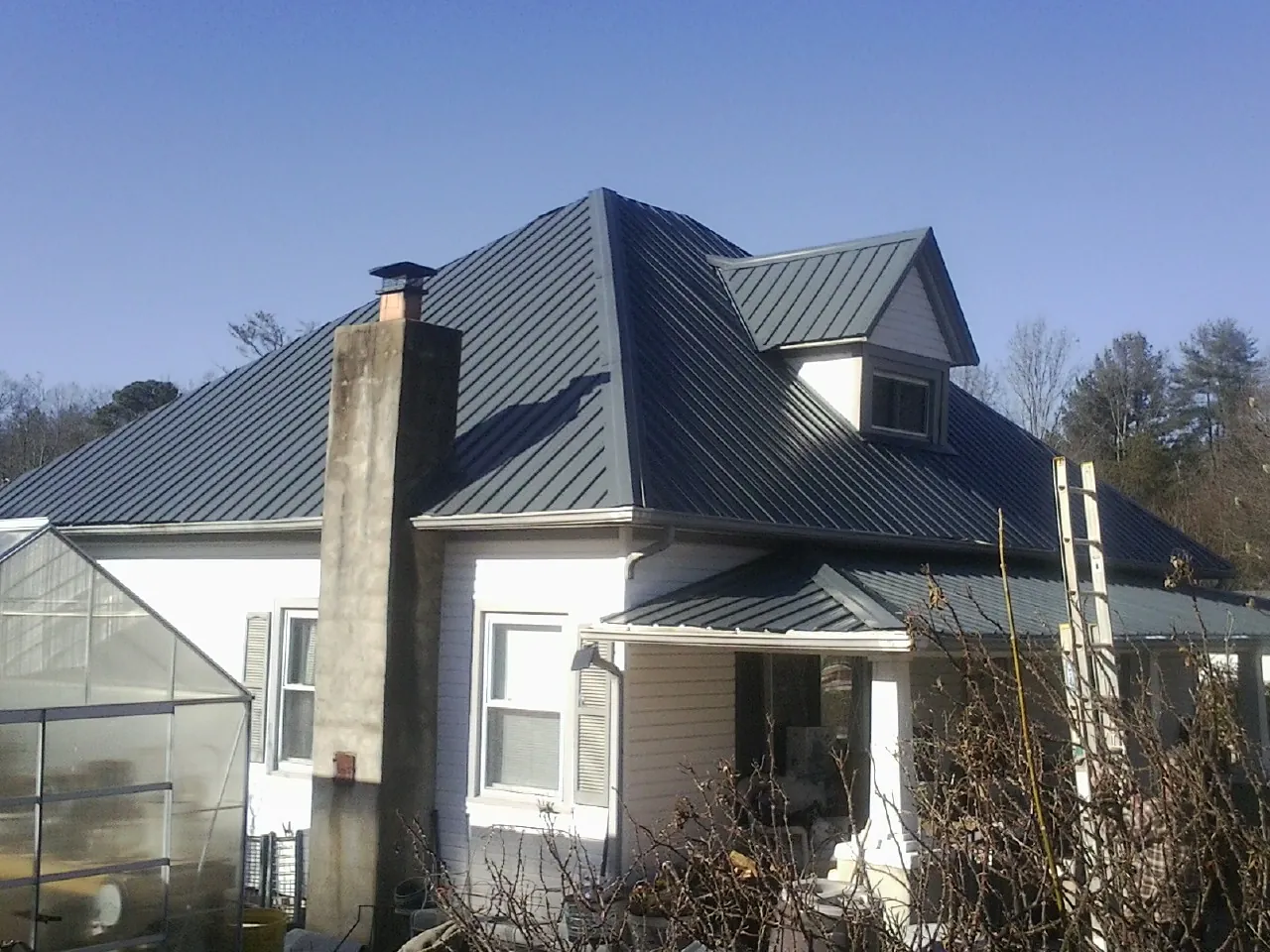 Dark blue standing seam metal roof on a white farmhouse with dormer — Slate & Tile Roof Repair by Roofing Brothers in Richlandtown