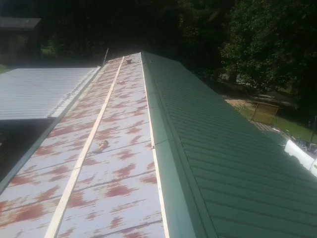 Old rusted panels beside newly installed green metal roofing — Wind Damage Roof Repair by Roofing Brothers in Richlandtown
