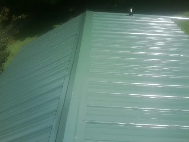 New green metal panels meeting at the ridge of a roof — Flat Roof Repair work by our crew in Richlandtown