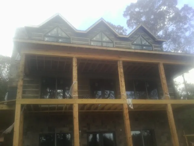 Dormers and porch framing on a large log home under construction — Roof Coating work by our crew in Richlandtown