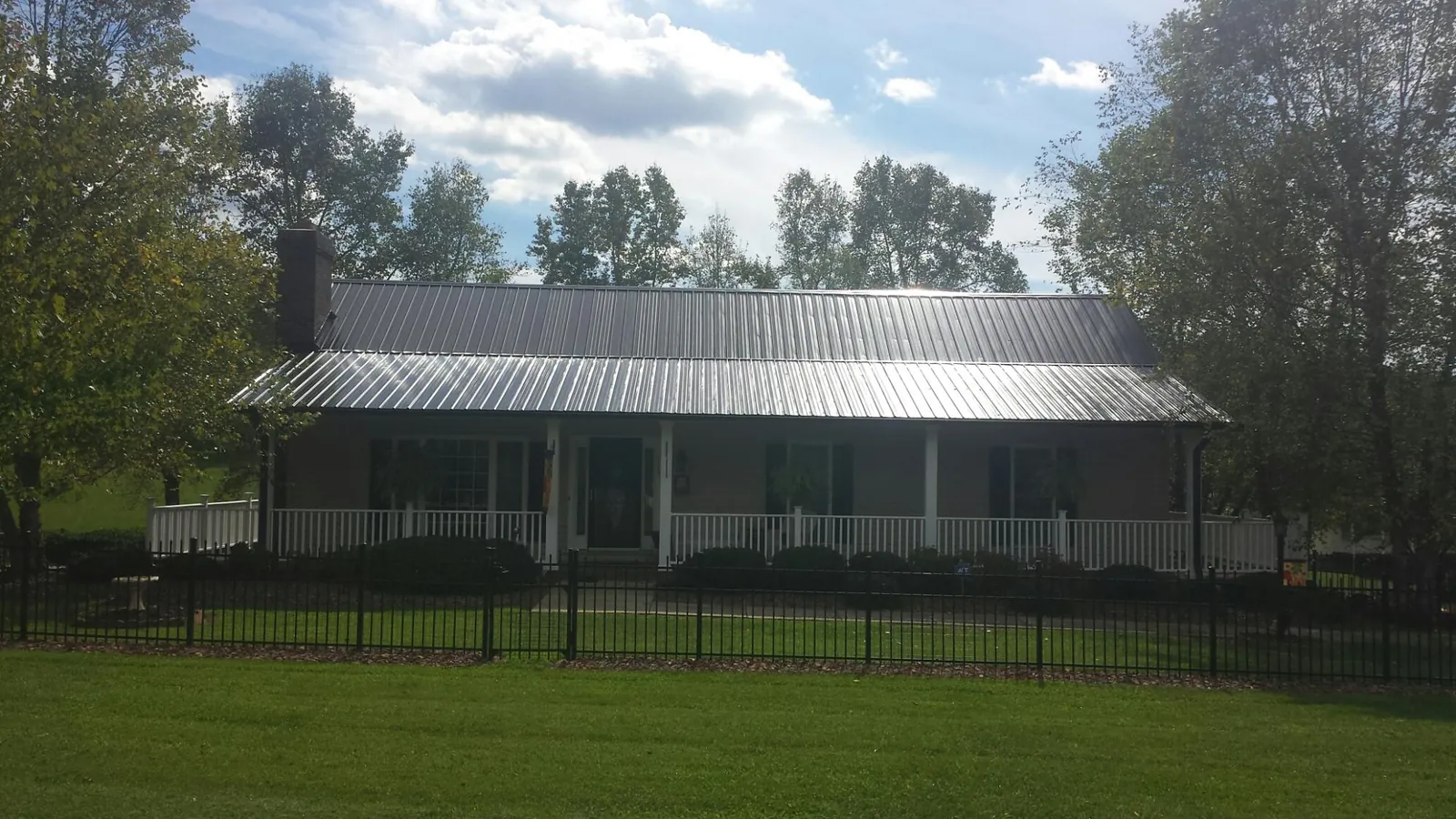 Gray metal roof on a brick ranch with a full width front porch — Gutter Guard Installation work by our crew in Richlandtown