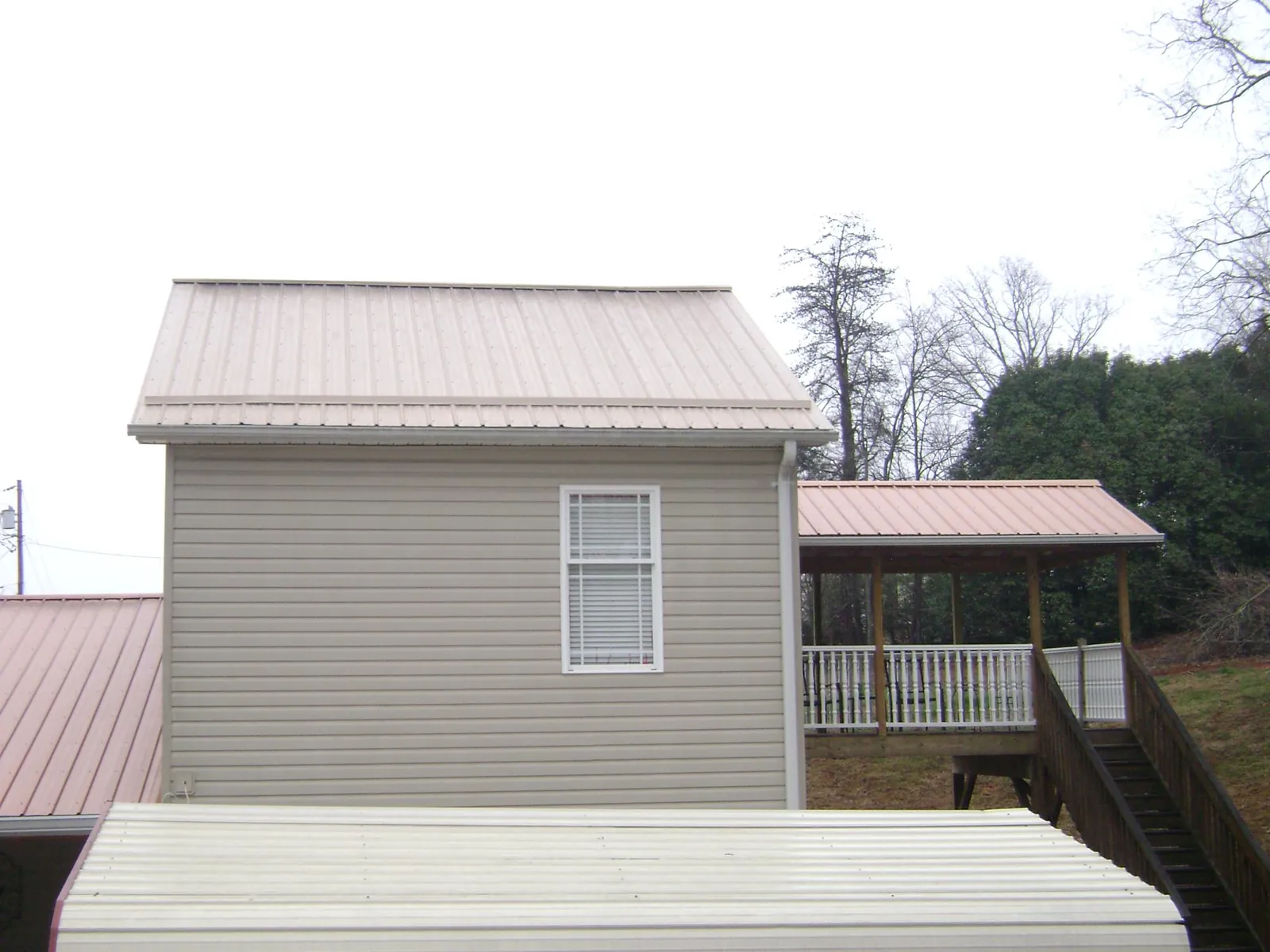 Tan metal roofs on a two story addition and attached porch, from a Roof Replacement job in Richlandtown