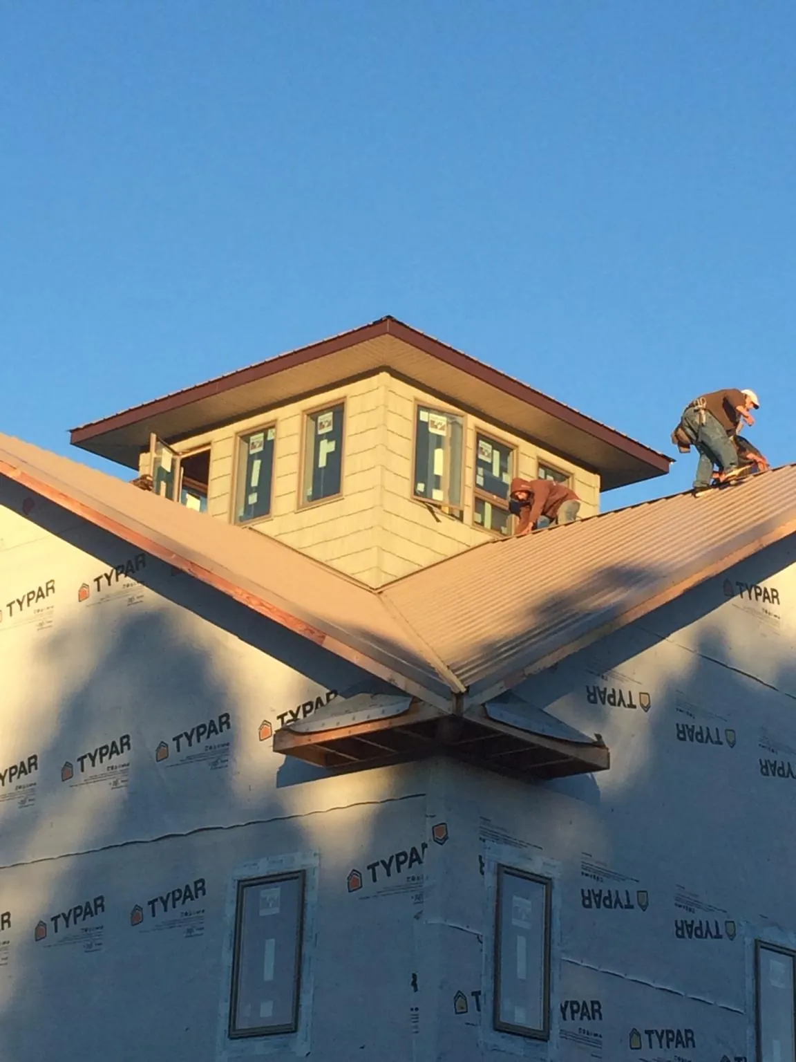 Roofers working around a rooftop cupola on a new metal roof at sunset — Roof Waterproofing in Richlandtown by Roofing Brothers